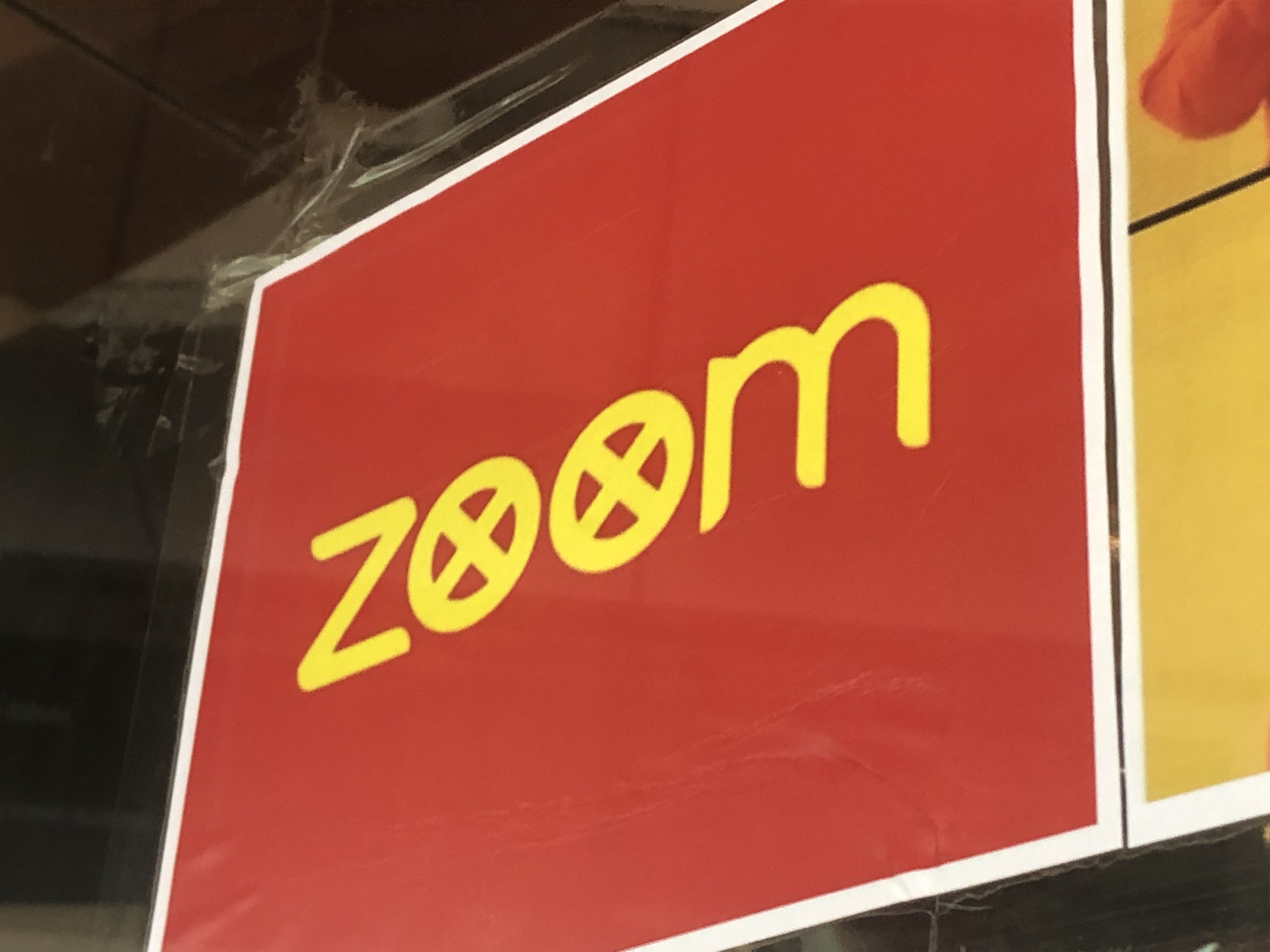 Fig. 3. Personal photograph of an anti-Zoom poster with Xs in each letter “o” in the word “Zoom” appended to a campus window. This photograph depicts a square red sign on a window. The sign is red with a white border and contains the word “zoom” in yellow font with the Os x-ed out.